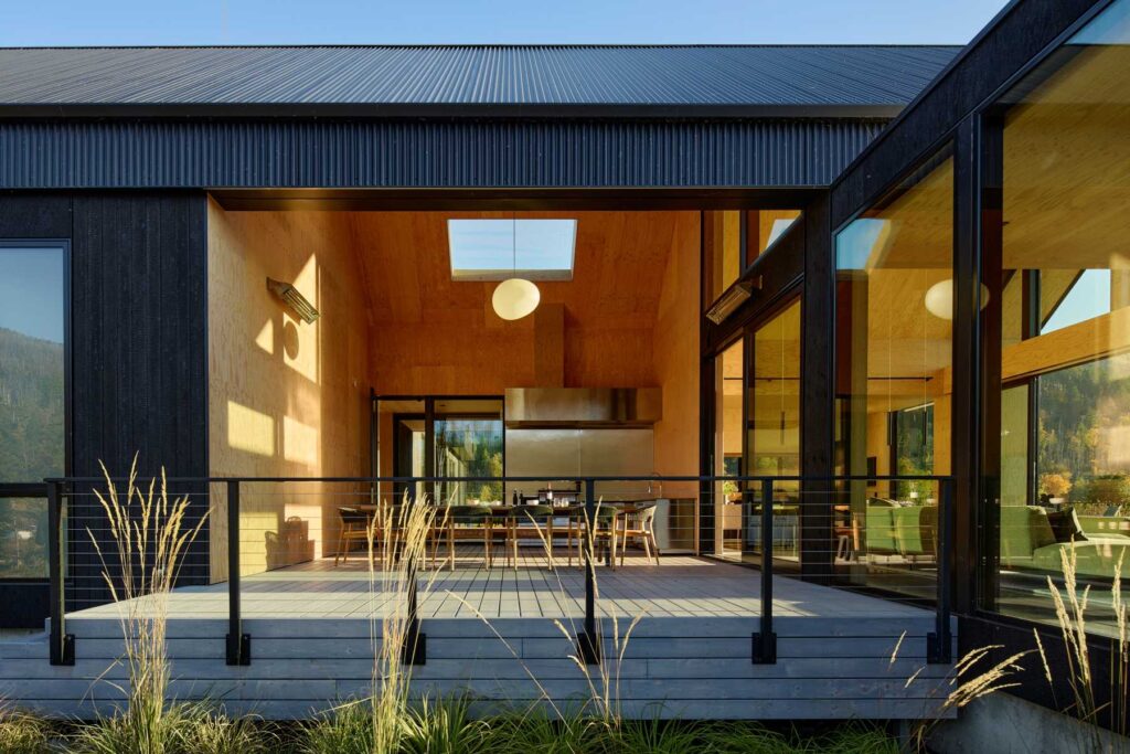A covered outdoor deck featuring a wood-lined ceiling, dining area, and seamless indoor-outdoor connection.