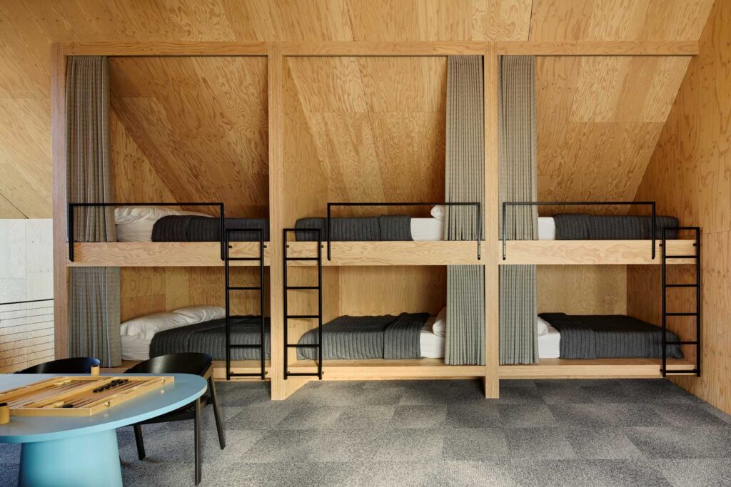 A thoughtfully designed shared bedroom featuring custom-built wooden bunk beds and simple furnishings.