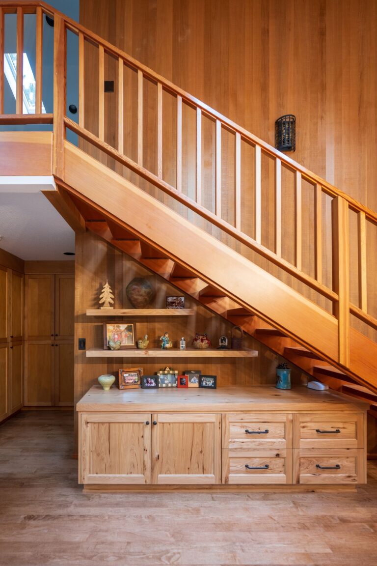 A beautifully crafted staircase with integrated shelving and cabinetry adds functionality and warmth to this rustic interior.