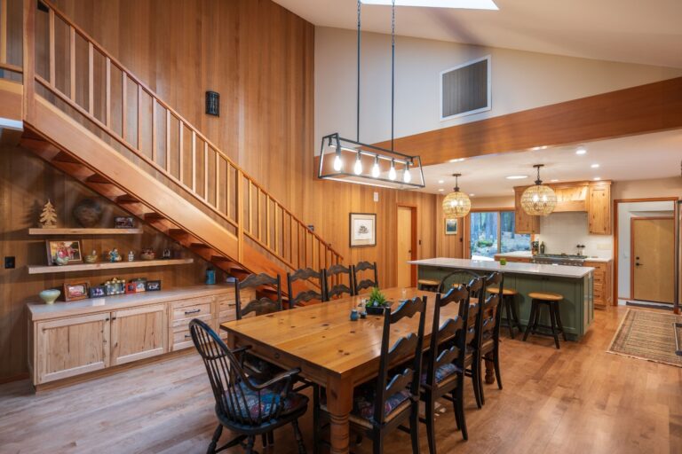 A warm, inviting space featuring a handcrafted staircase, spacious dining table, and a modern kitchen with rustic touches.
