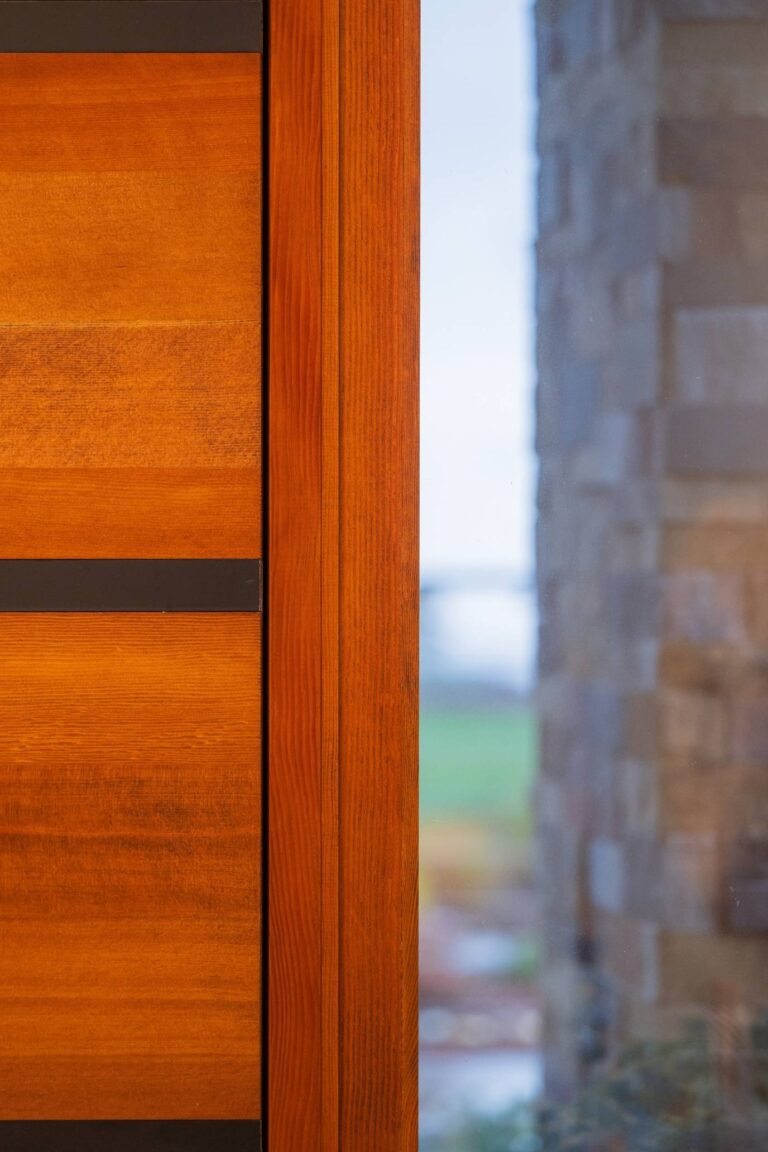 A sleek wood entry door with horizontal metal accents paired with a glass panel for natural light and style.