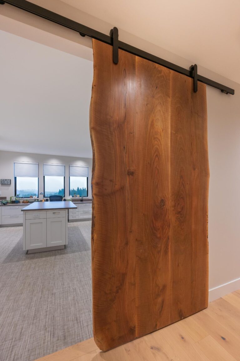 A stunning live-edge wood barn door with sleek black hardware adds natural warmth to this modern home.